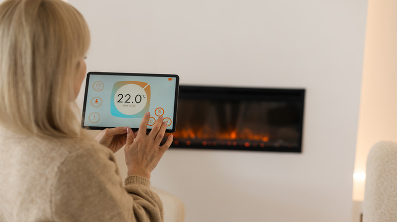 Woman controlling a smart fireplace with her smart hub app on tablet