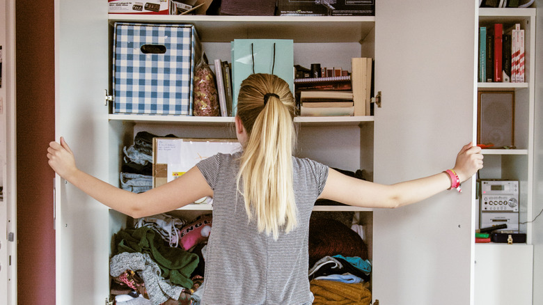 woman opening doors of disorganized closet