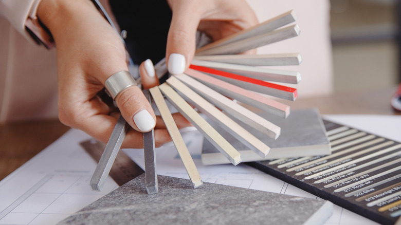 A woman chooses a grout line color from samples