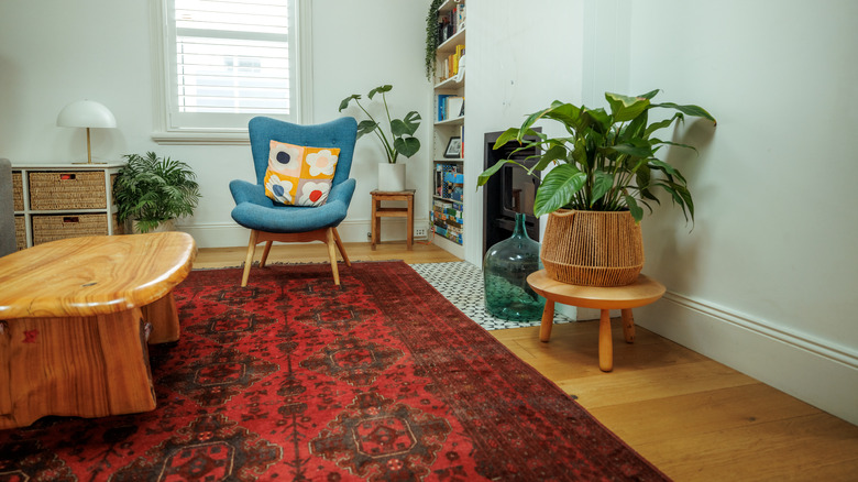 A bold red rug in a neutral room with minimal wood decor and houseplants