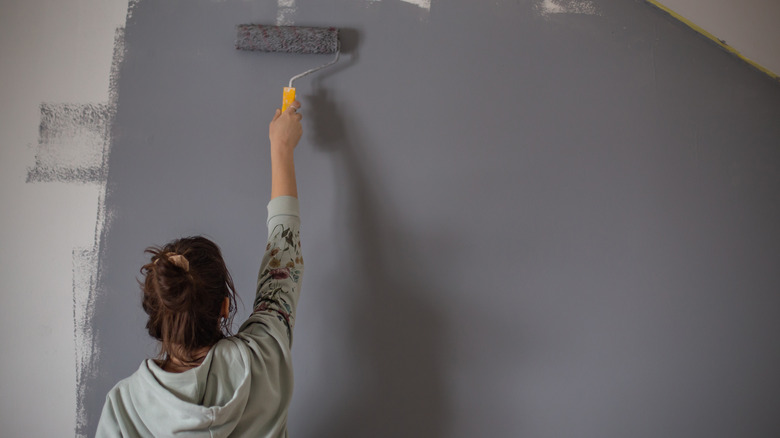 Woman painting wall gray color