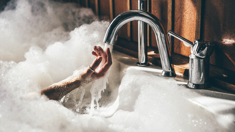 person running hand under bathtub faucet