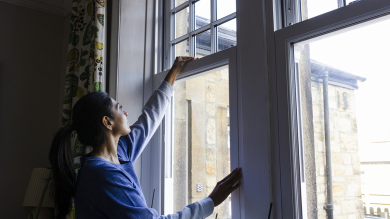 Woman attempting to open window, her lights are off