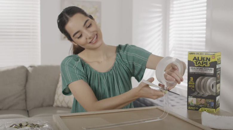 A smiling woman cuts a piece of Alien Tape