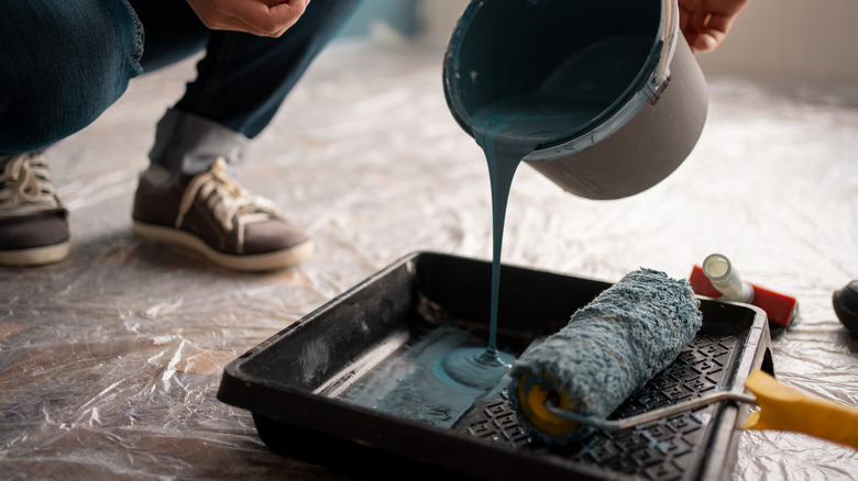 person pouring paint into tray