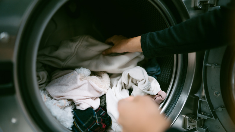 Hands putting dirty laundry in the washing machine