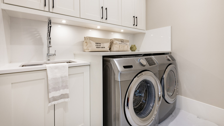 side by side laundry with sink and folding shelf with under-cabinet lighting