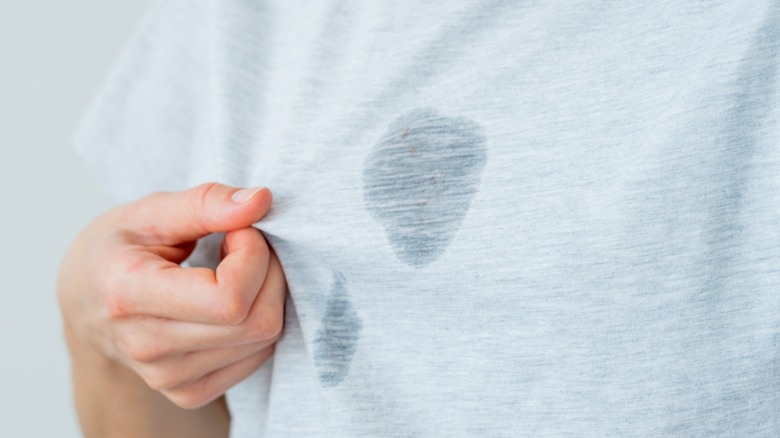 person holding grease stain on gray shirt