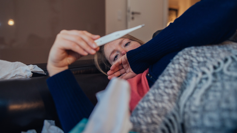 woman looking at thermometer with hand over mouth