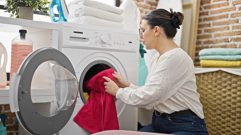 woman putting bright pink towel in washer