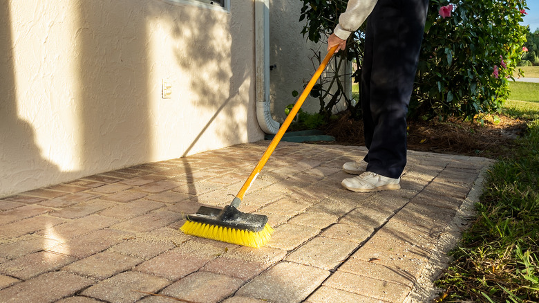 Person sweeping brick pavers