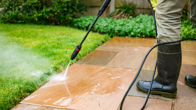 Person pressure washing stone pavers