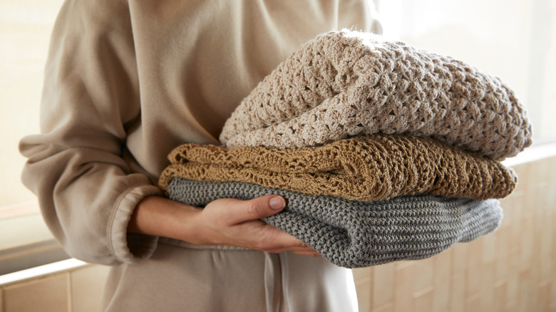 woman holding hand knitted blankets 