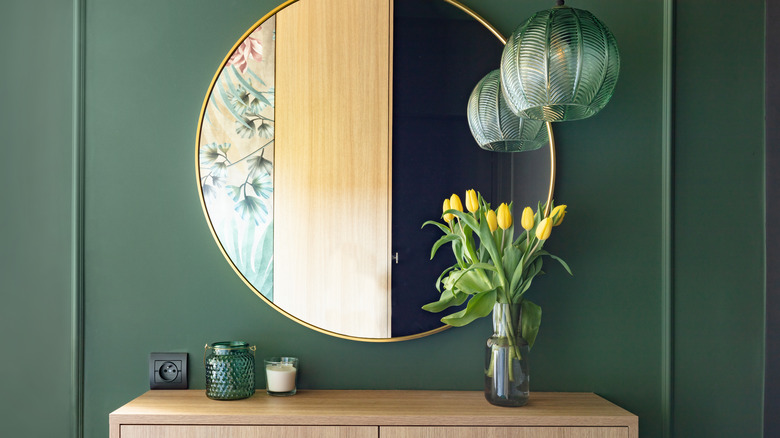 mirror at entryway on green wall with molding