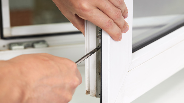 man using screwdriver on window