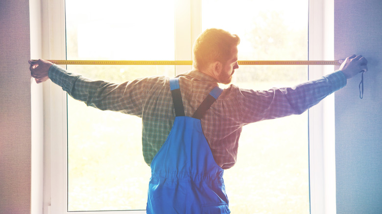 man measuring window