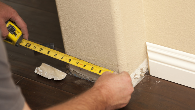 Measuring the wall for baseboard installation