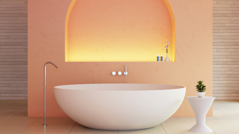 A soaking tub in front of peach wall with warm lighting