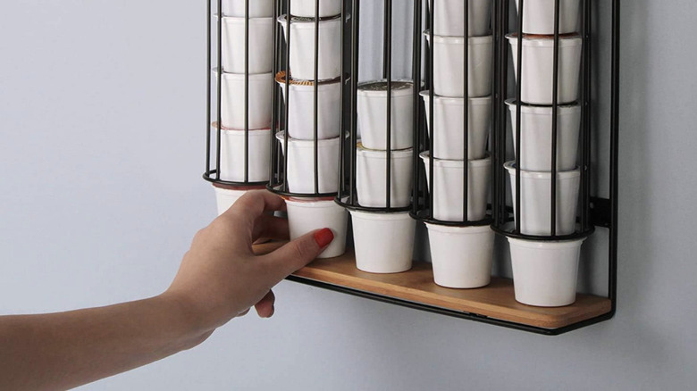 Person's hand grabbing coffee pod from wall hanger