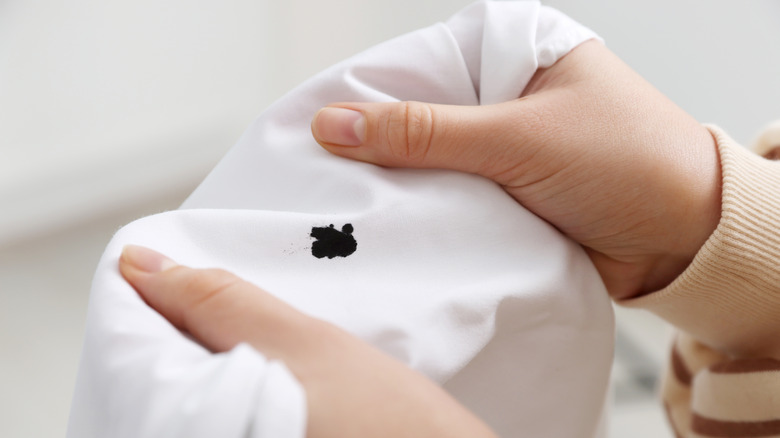 Hands holding stained white shirt