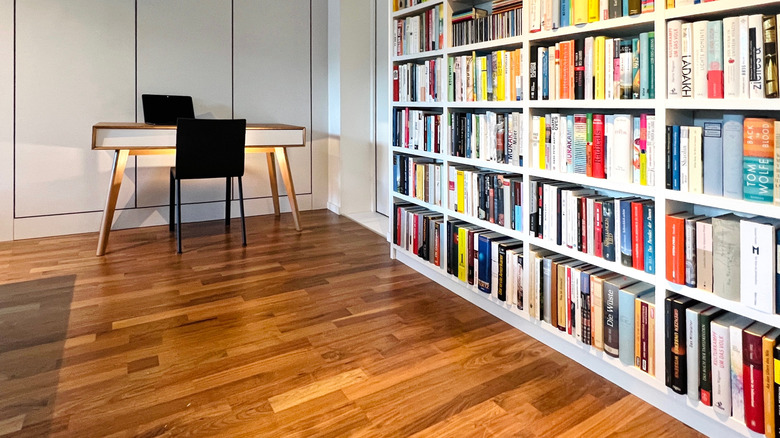 Organized books on a bookshelf with a nearby desk