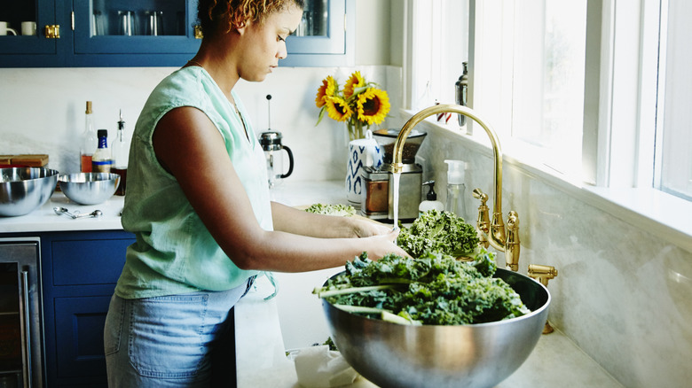 Woman washing vegetables at a kitchen sink