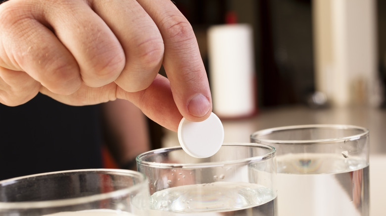 hand dropping Alka-seltzer into water