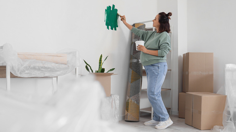 Pregnant woman painting wall green