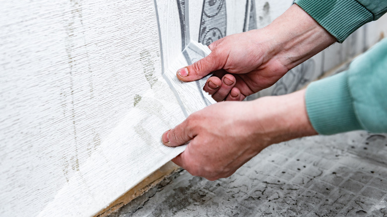 close up of hands removing wallpaper