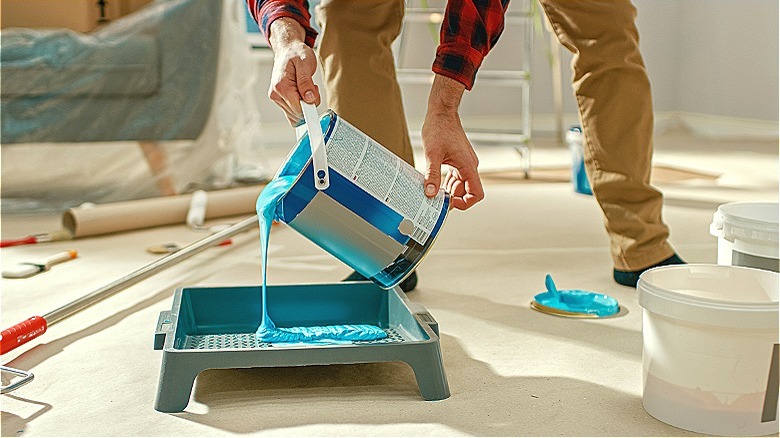 Person pouring paint around supplies