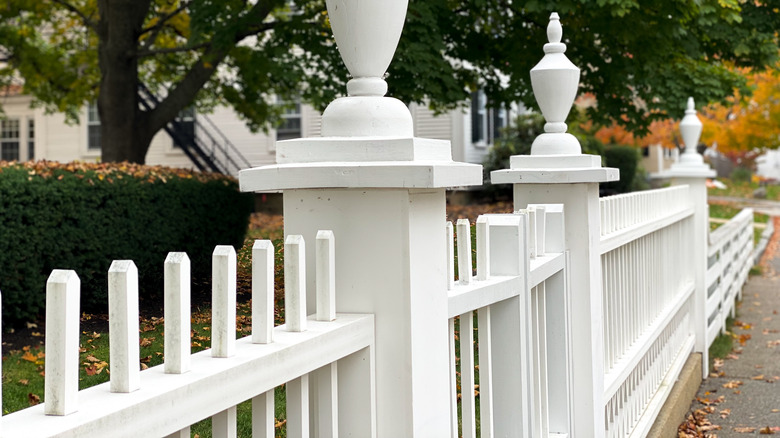 A white fence built along a sidewalk