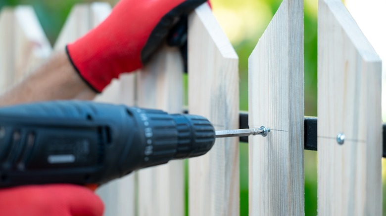 Person screwing fence boards into the frame