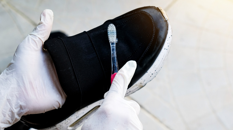 Person scrubbing shoe with toothbrush 