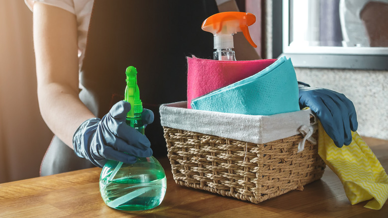 woman holding basket of cleaning supplies