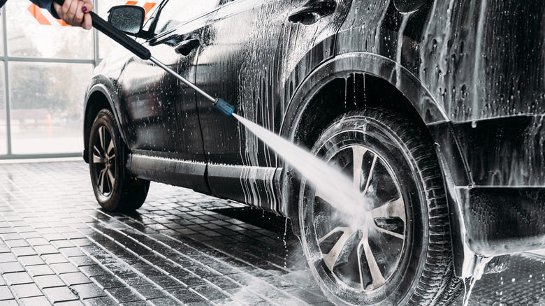 car wash hose cleaning car's tires