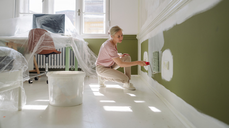 Woman painting a wall in her home.