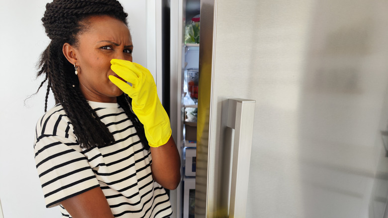 Woman smelling stinky fridge