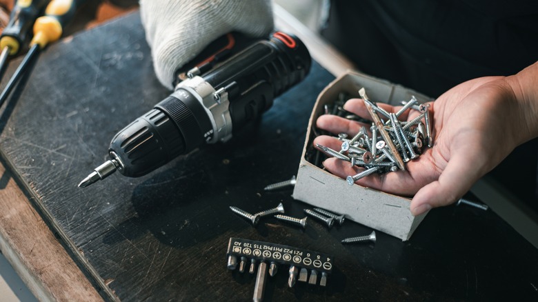 Person holding screws and drill