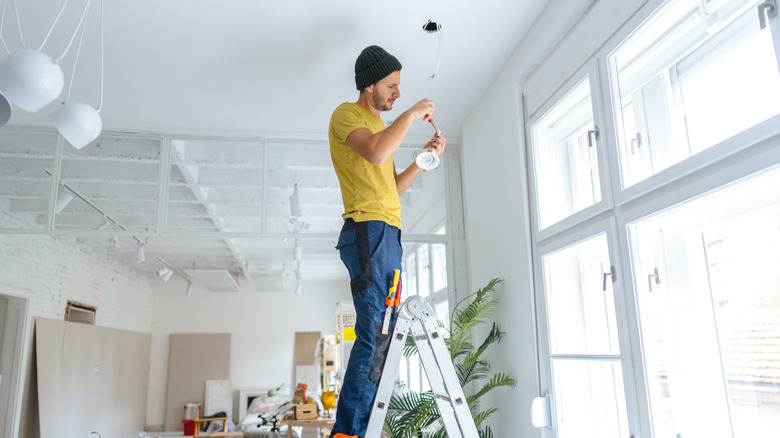 Man standing on ladder and working on ceiling