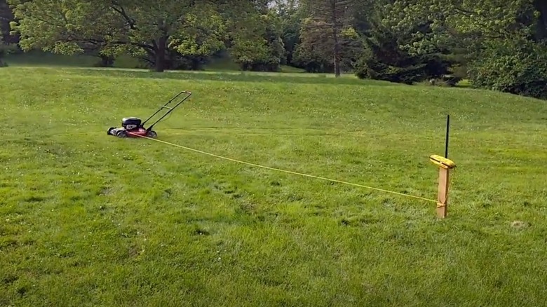 Lawnmower tied to stake in yard 