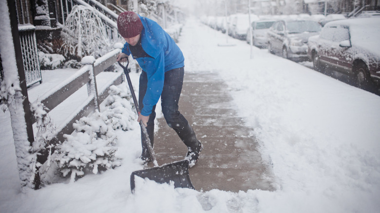 A person shoveling snow outside of their home.