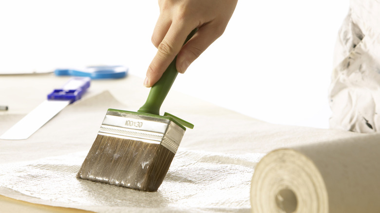 Hand applying paste to wallpaper