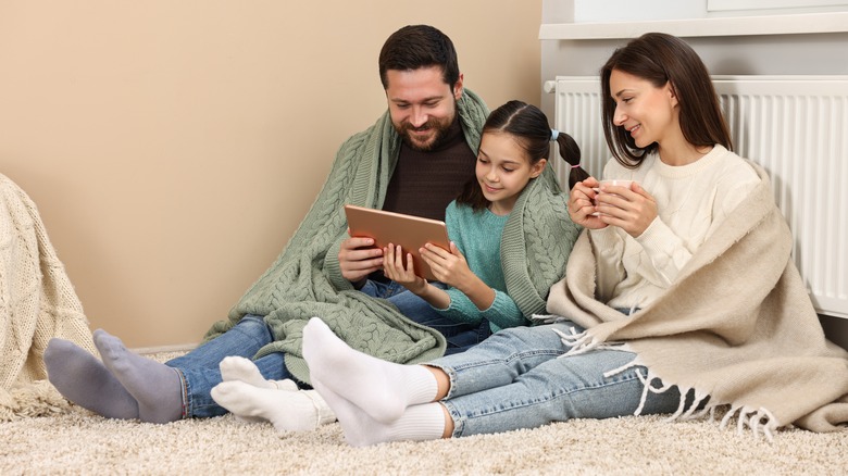 A family sits at home under blankets.