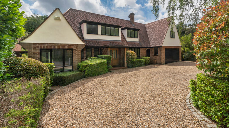 A two-story house with a pristine gravel drive