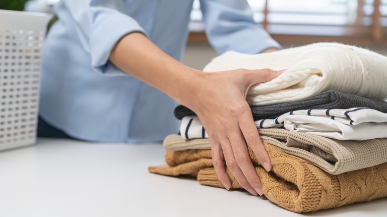 Person holding stack of folded knit clothing