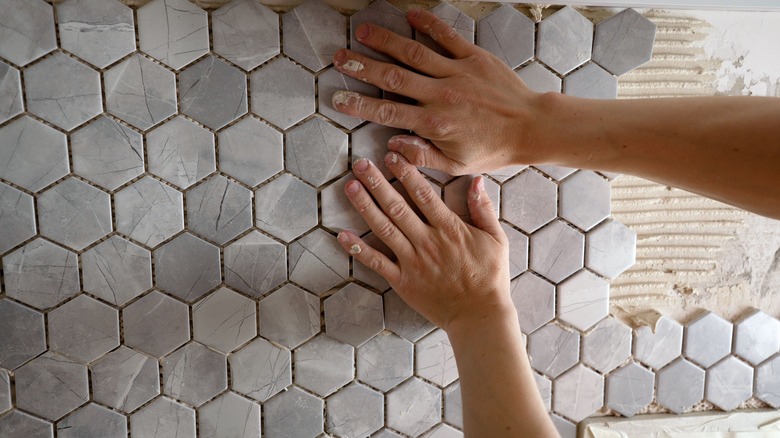 person installing bathroom tile