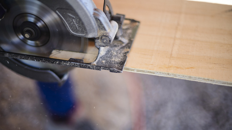 A circular saw cutting a piece of plywood