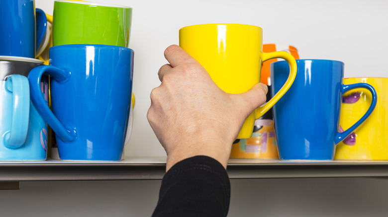 woman grabbing cup from shelf 