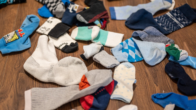 Messy mismatched socks on wooden floor