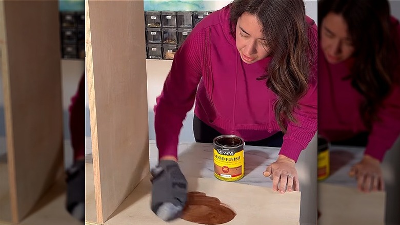 Woman using plastic bag and sock to stain wooden furniture